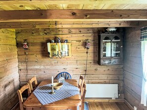 Cozy cabin interior with a dining table, chandelier, and wooden cabinet.
