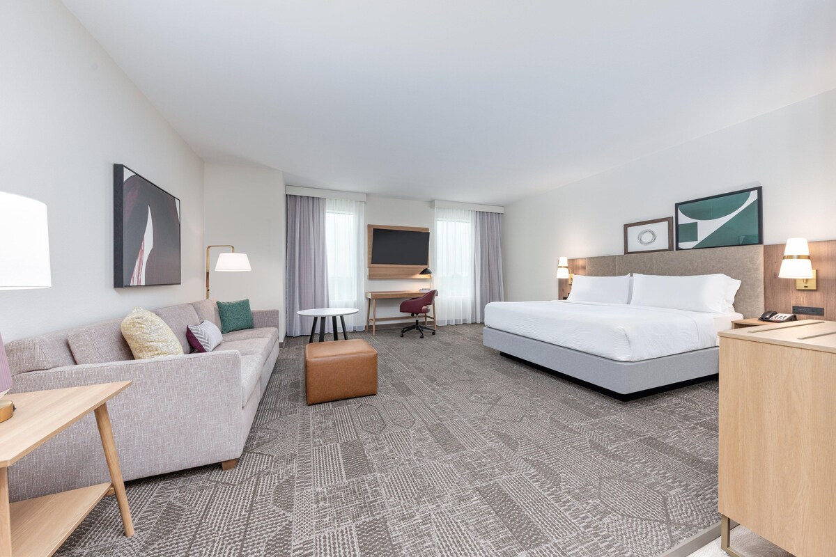 A hotel room with a bed, a sofa, a desk, and a chair.