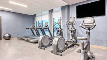 Een sportschool met loopbanden, elliptische trainers en een hometrainer.