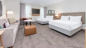 A hotel room with a sofa, two single beds, a small table, and a chair. - Staybridge Suites Port Arthur Mall Area (Port Arthur)