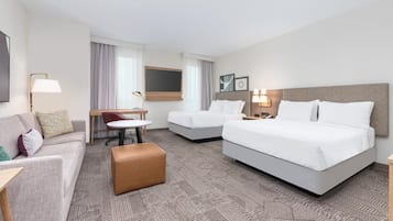 Ett hotellrum med en soffa, två enkelsängar, ett litet bord och en stol.