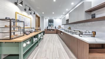A modern kitchen with a marble countertop, wooden cabinets, and a display case with baked goods.