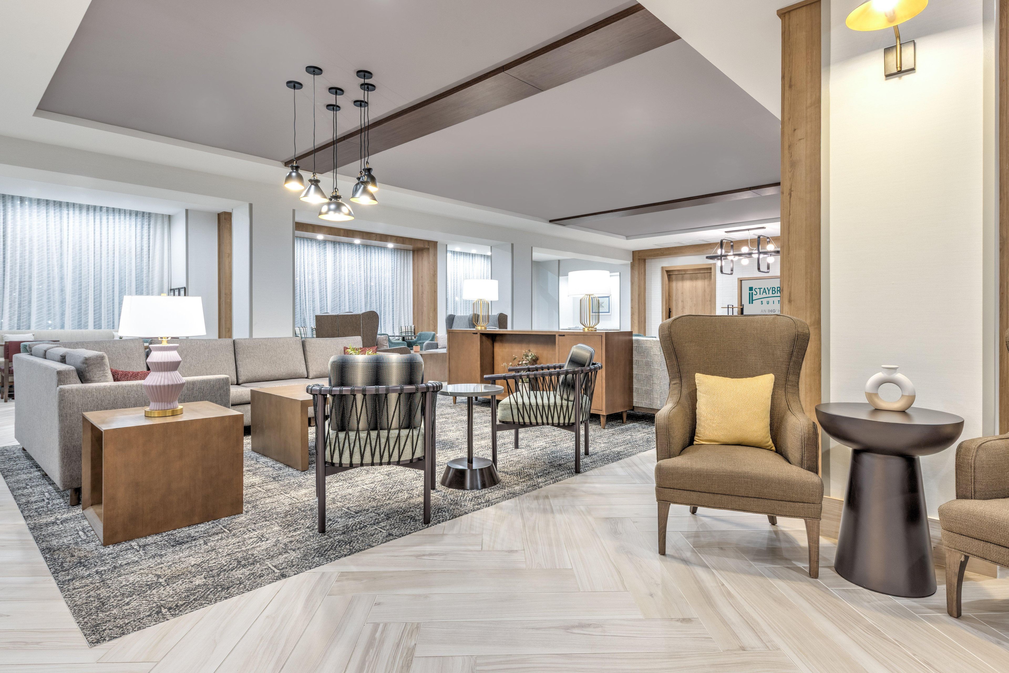En modern hotelllobby med en soffa, fåtöljer, ett soffbord och en matplats.