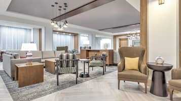 En modern hotelllobby med en soffa, fåtöljer, ett soffbord och en matplats.