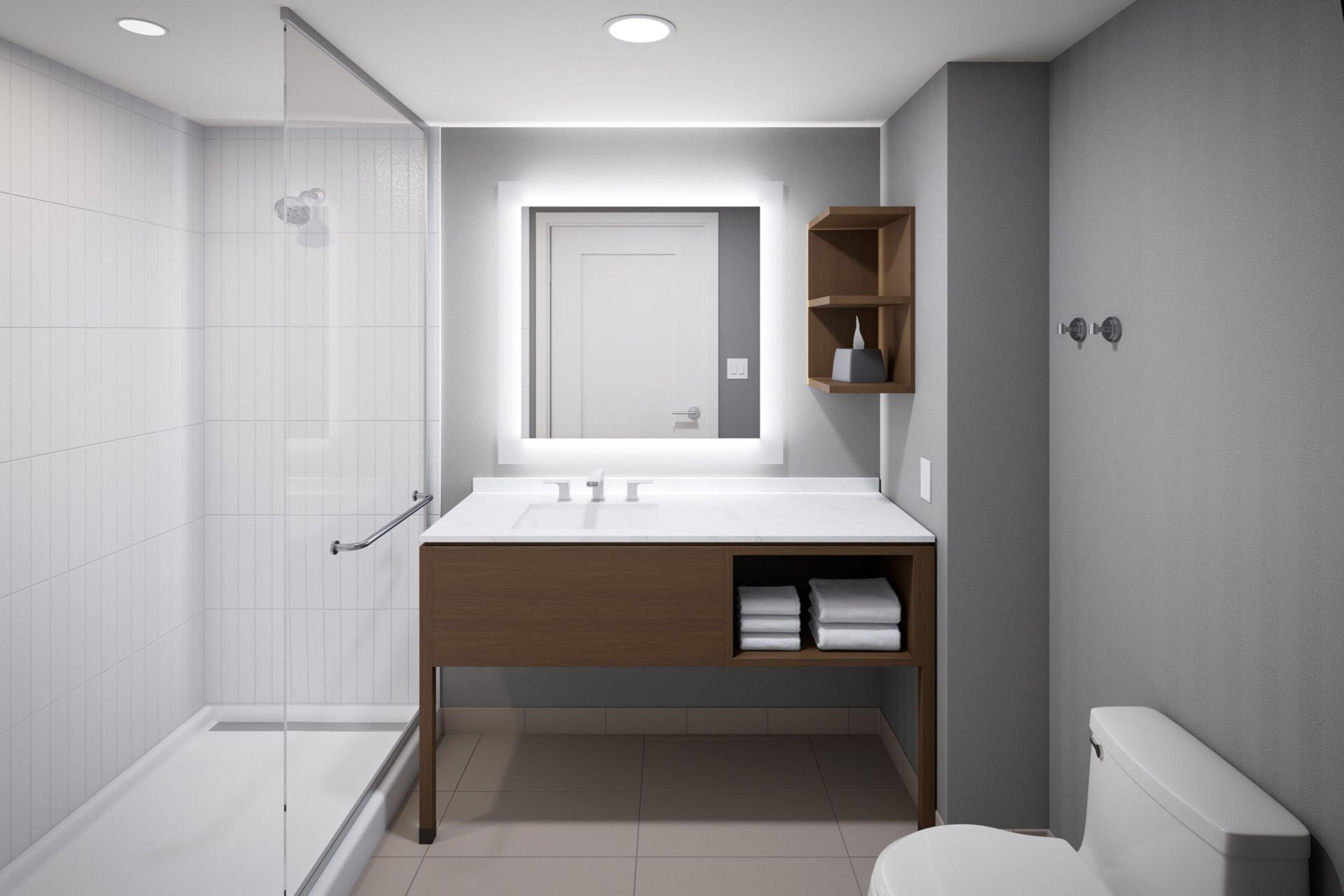 A modern bathroom with a glass shower enclosure, a white sink with a wooden vanity, and a toilet.