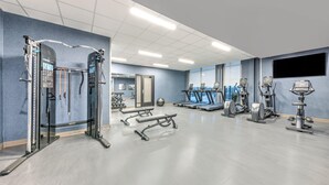 A modern gym with various exercise equipment, including treadmills, ellipticals, and weight machines.