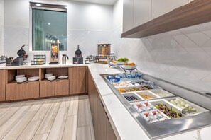 A modern kitchen with a breakfast bar, white tiles, wooden cabinets, and a variety of food and drink options. - Staybridge Suites Port Arthur Mall Area (Port Arthur)