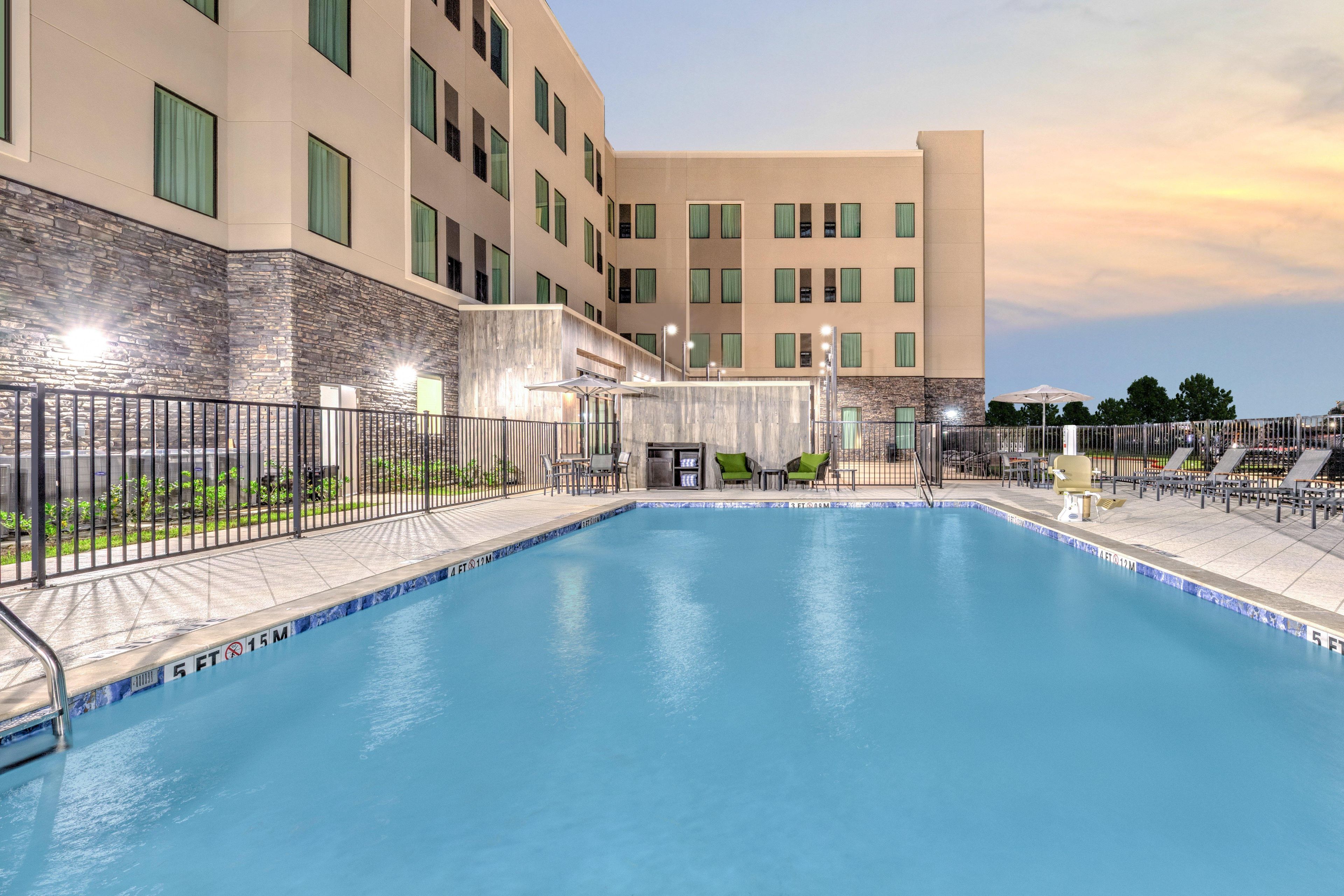 A swimming pool with a stone wall and a building in the background.