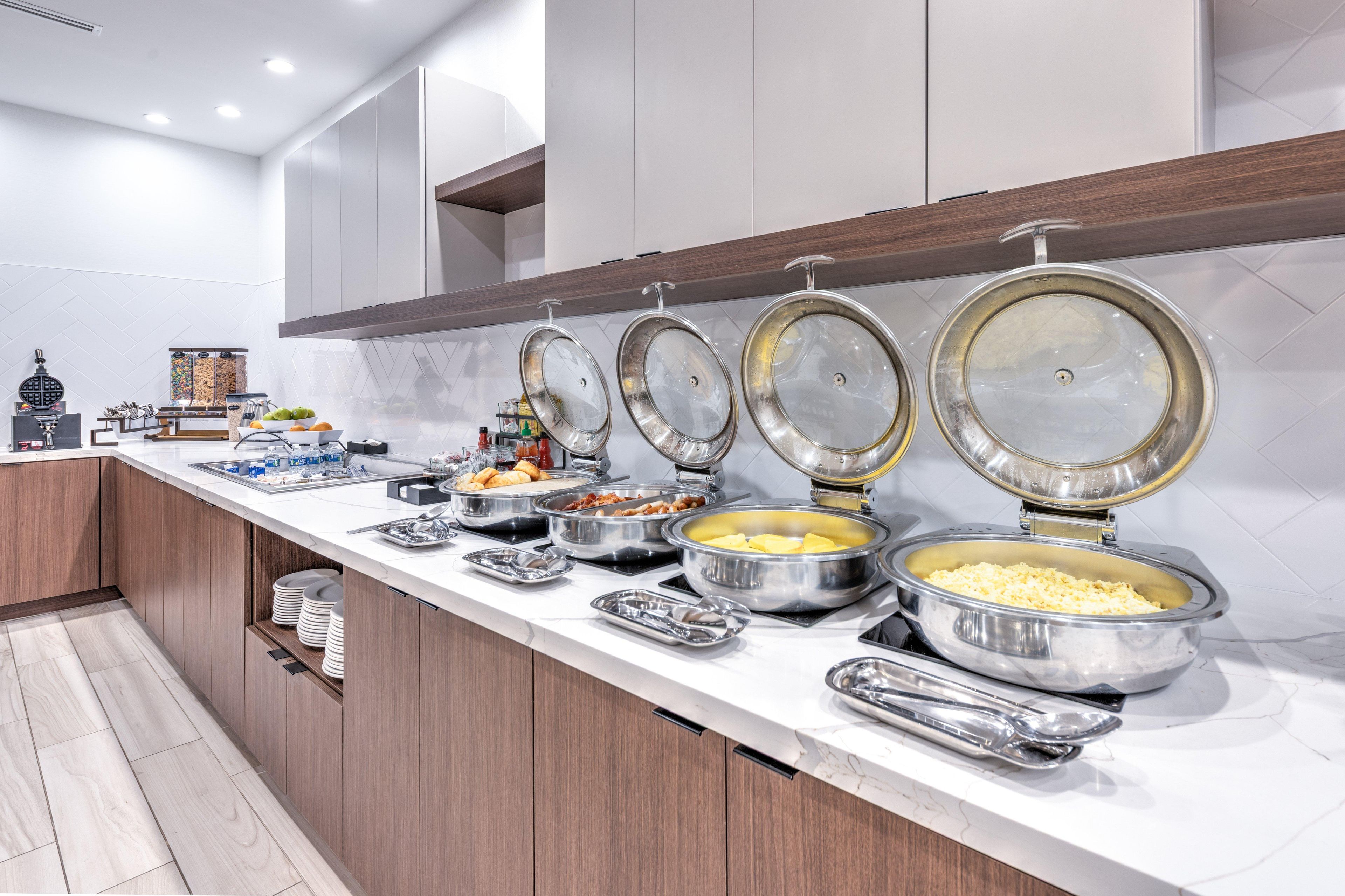 A buffet setup with various food items and utensils on a marble countertop.