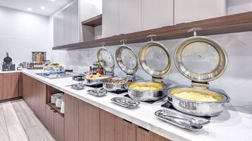 A buffet setup with various food items and utensils on a marble countertop.