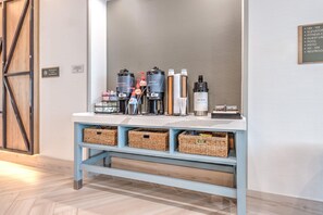A reception desk with a coffee station, baskets, and a sign listing amenities like elevators, fitness center, and pool. - Staybridge Suites Port Arthur Mall Area (Port Arthur)