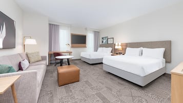 Ett hotellrum med en stor säng, en soffa, ett litet bord och ett skrivbord.