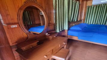 Een houten kamer met een bed, een dressoir, een spiegel en gordijnen.