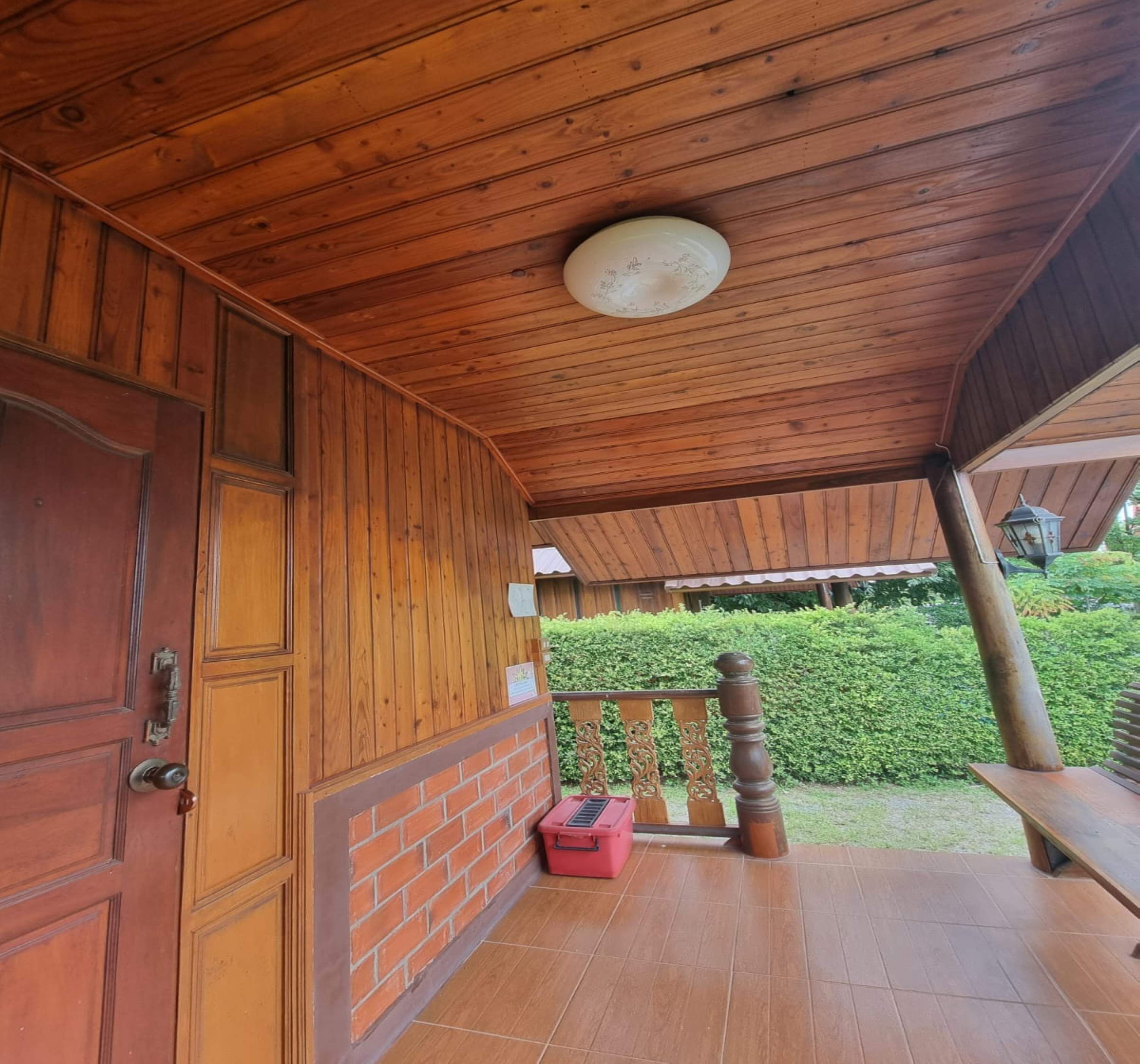 A wooden porch with a brick wall, a door, and a small red object on the floor.