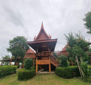 A traditional wooden building with a steeply pitched roof and a central staircase leading to an upper level. - Metathsana Resort (Ayutthaya)