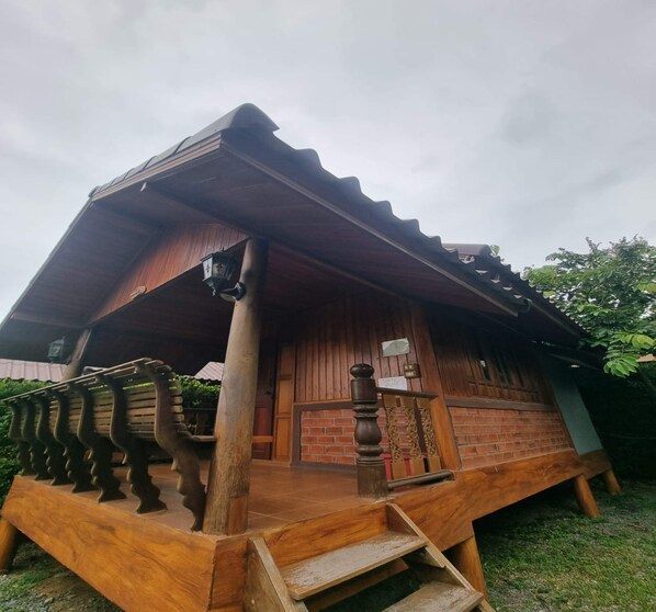 A wooden house with a porch, a staircase, and a brick wall. - Metathsana Resort (Ayutthaya)
