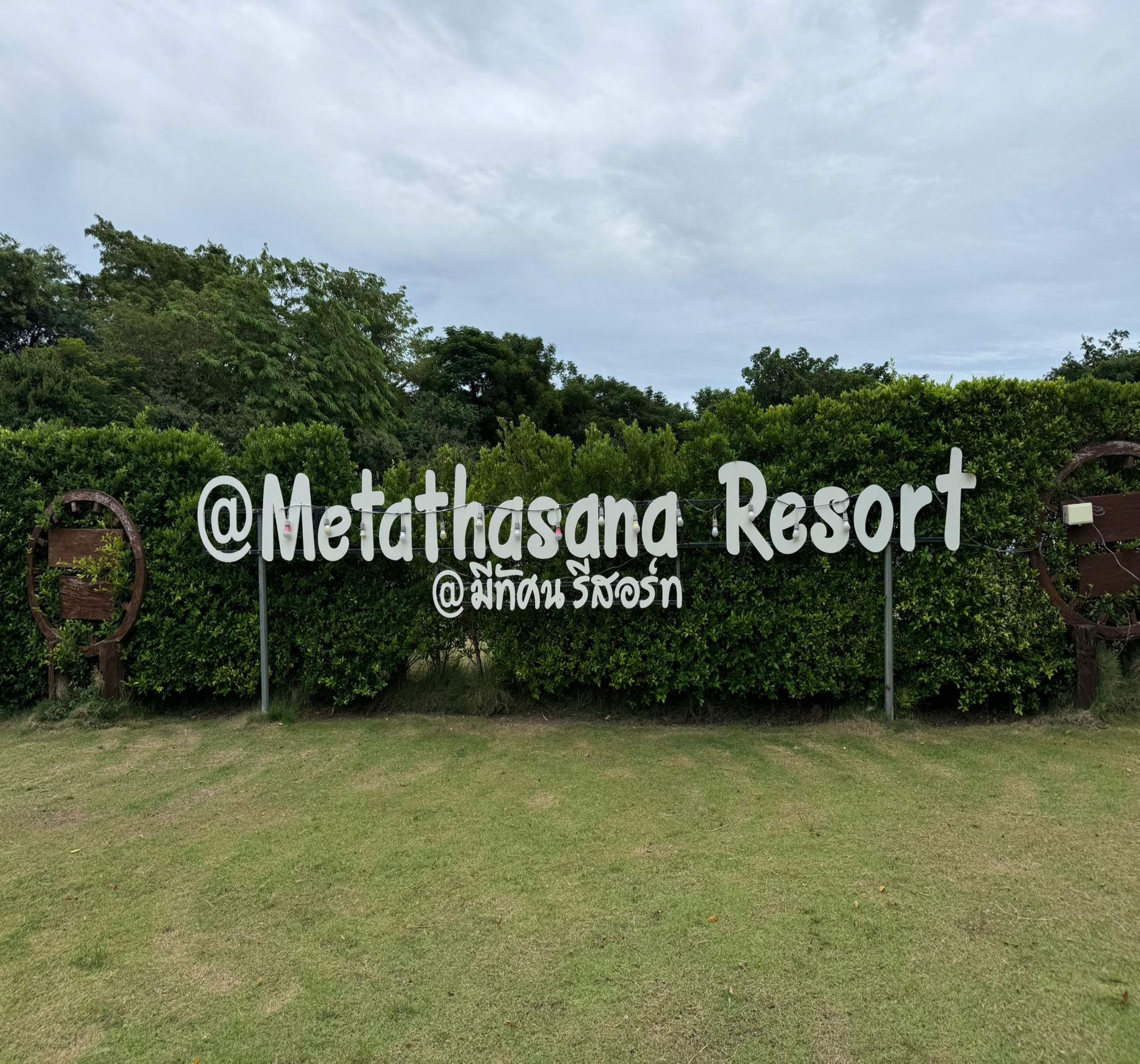 A sign for Metathasana Resort with a hashtag and a name in a non-English script.