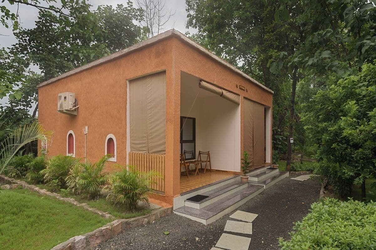 A small, single-story building with a covered porch, a small table and chairs, and a door leading inside.
