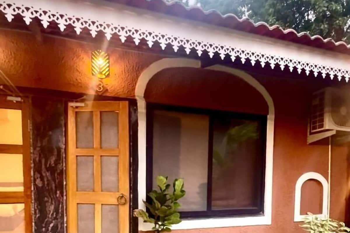 A house with a tiled entrance, a wooden door, a window with a white frame, and a small porch area with steps.