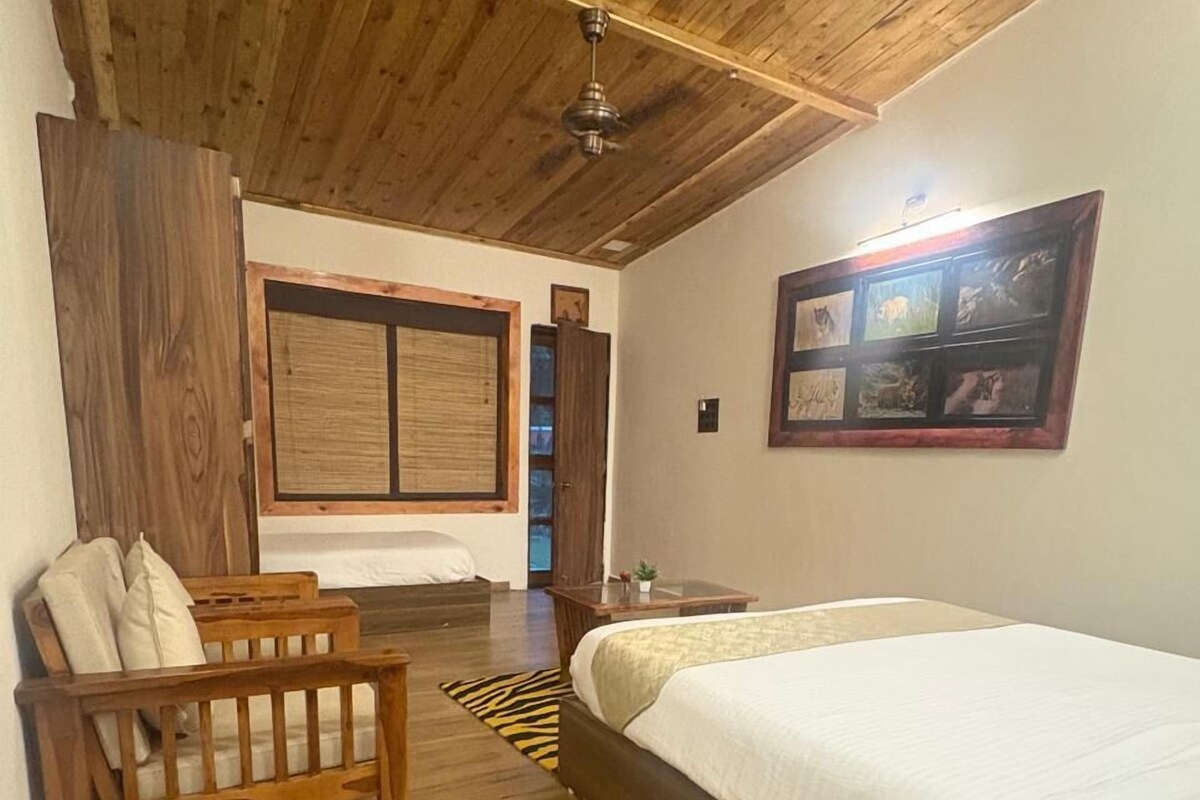 A bedroom with a wooden ceiling, a bed, a wooden bench, a window with blinds, and a framed picture on the wall.
