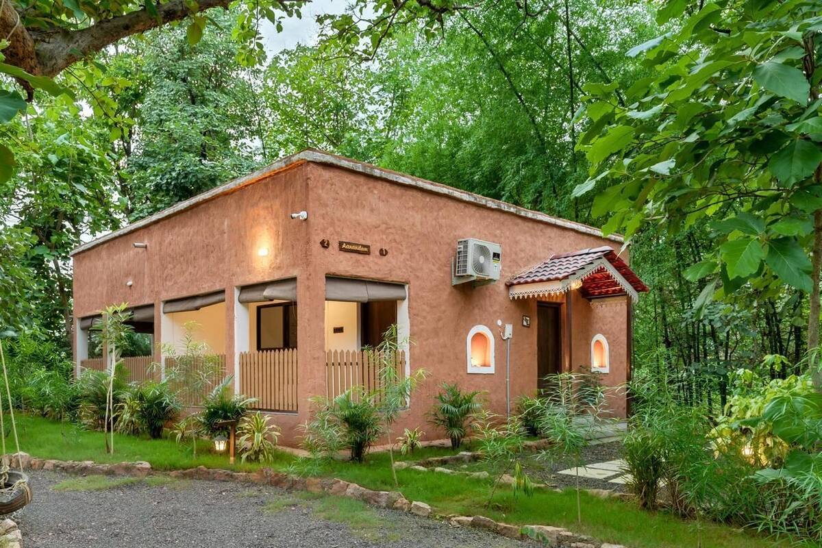 A rustic building with a brown facade, a small porch, and a gravel driveway.