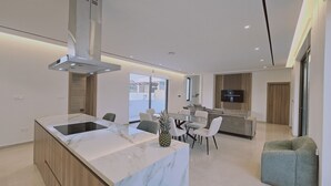 Een moderne keuken met een marmeren aanrecht, een ingebouwde kookplaat en een eethoek met een tafel en stoelen.