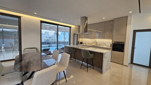 Een moderne keuken met een marmeren aanrechtblad, roestvrijstalen apparatuur en een groot raam met uitzicht op een zwembad.