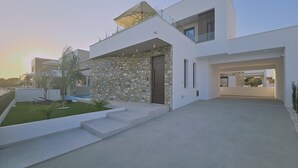 Ein modernes Haus mit Naturstein-Fassade, Flachdach und großem Glasfenster.