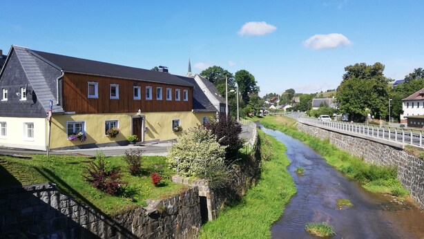 Ein Gebäude am Flussufer mit Steinmauer und Brücke.