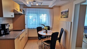 Eine kompakte Küche mit Essbereich, ausgestattet mit einem runden Tisch, Stühlen und einer Kaffeemaschine.
