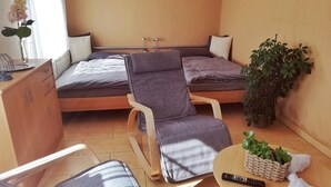 Ein gemütlicher Raum mit Bett, Sessel, kleinem Tisch und einer Zimmerpflanze.