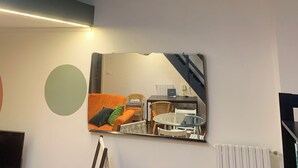 A room with a bed, a round table with chairs, a clock, and an air conditioning unit on the wall. - Loft nei caruggi in the heart of superb Genova (Genova)