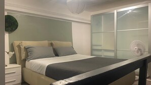 A bedroom with a bed, nightstand, and a large window with blinds. - Loft nei caruggi in the heart of superb Genova (Genova)