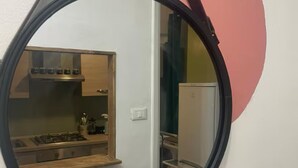 A round mirror reflecting a kitchen area with a microwave, stove, and cabinets. - Loft nei caruggi in the heart of superb Genova (Genova)