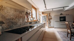 Une cuisine moderne dotée d’un plan de travail en granit, d’un évier encastré et d’un coin repas en bois avec une chaise.