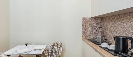 A compact kitchen with a dining table, two chairs, a coffee maker, and a kettle.