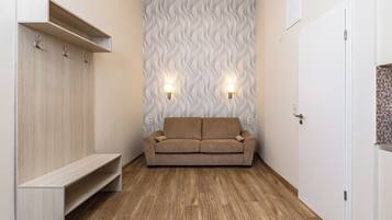A modern room with a wooden floor, a beige sofa, a built-in bench, and a patterned wall.