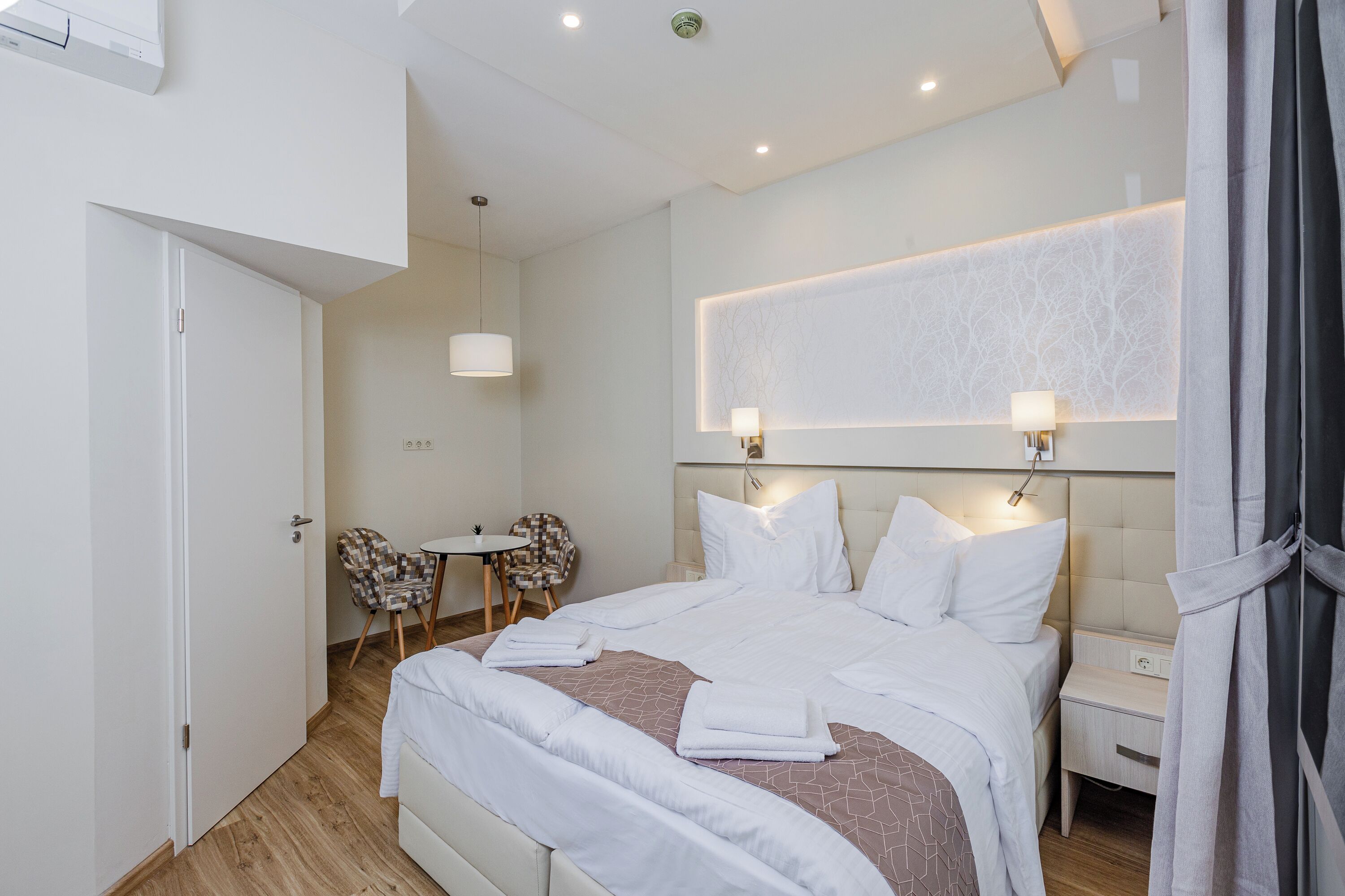 Habitació d'hotel amb un llit, taules de nit, un escriptori i una cadira.