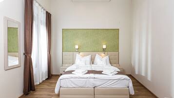 A hotel room with a large bed, two bedside lamps, a headboard, and a mirror on the wall.