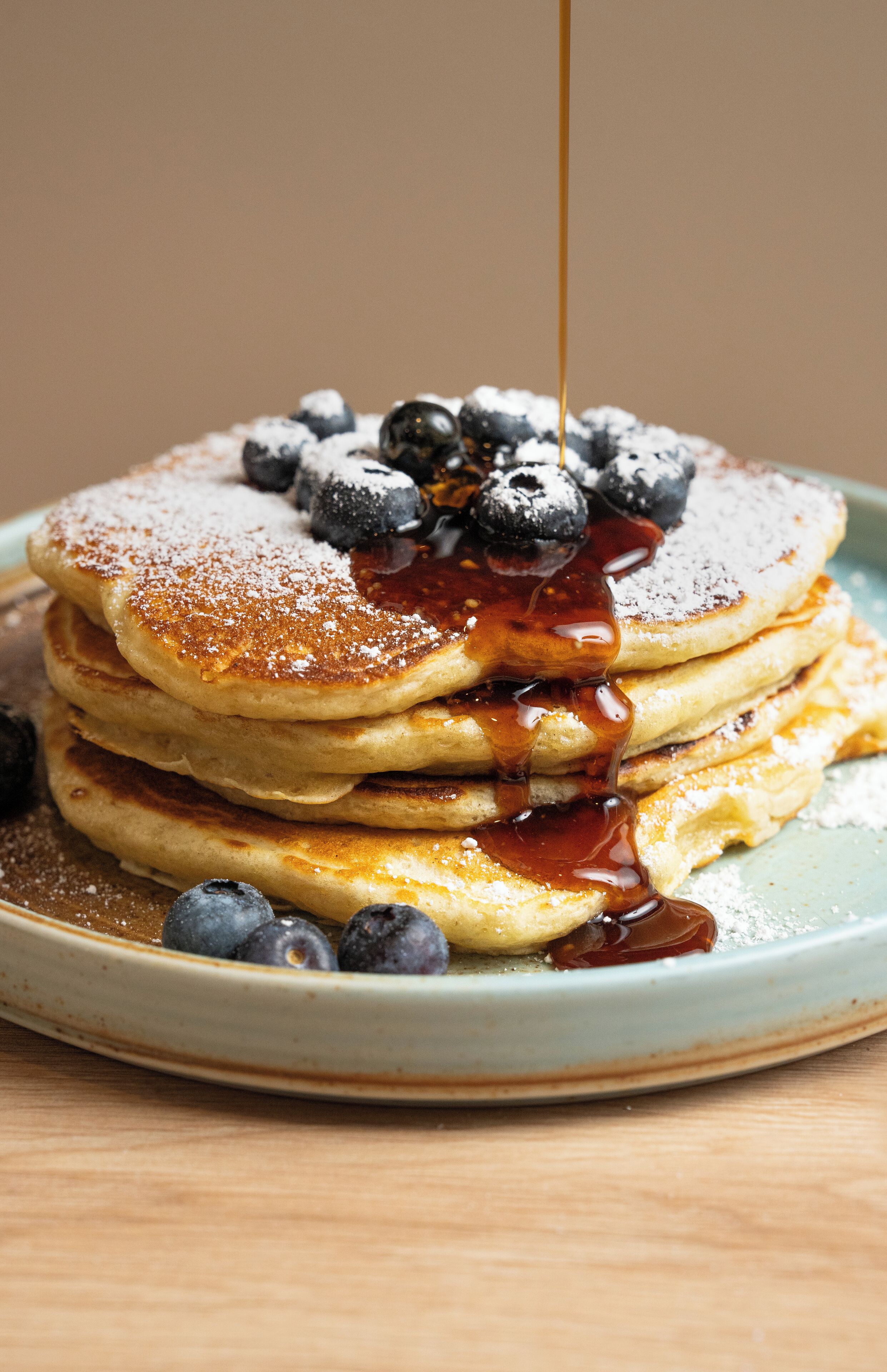 A stack of pancakes with blueberries and syrup on a plate.