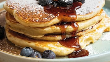 A stack of pancakes with blueberries and syrup on a plate.