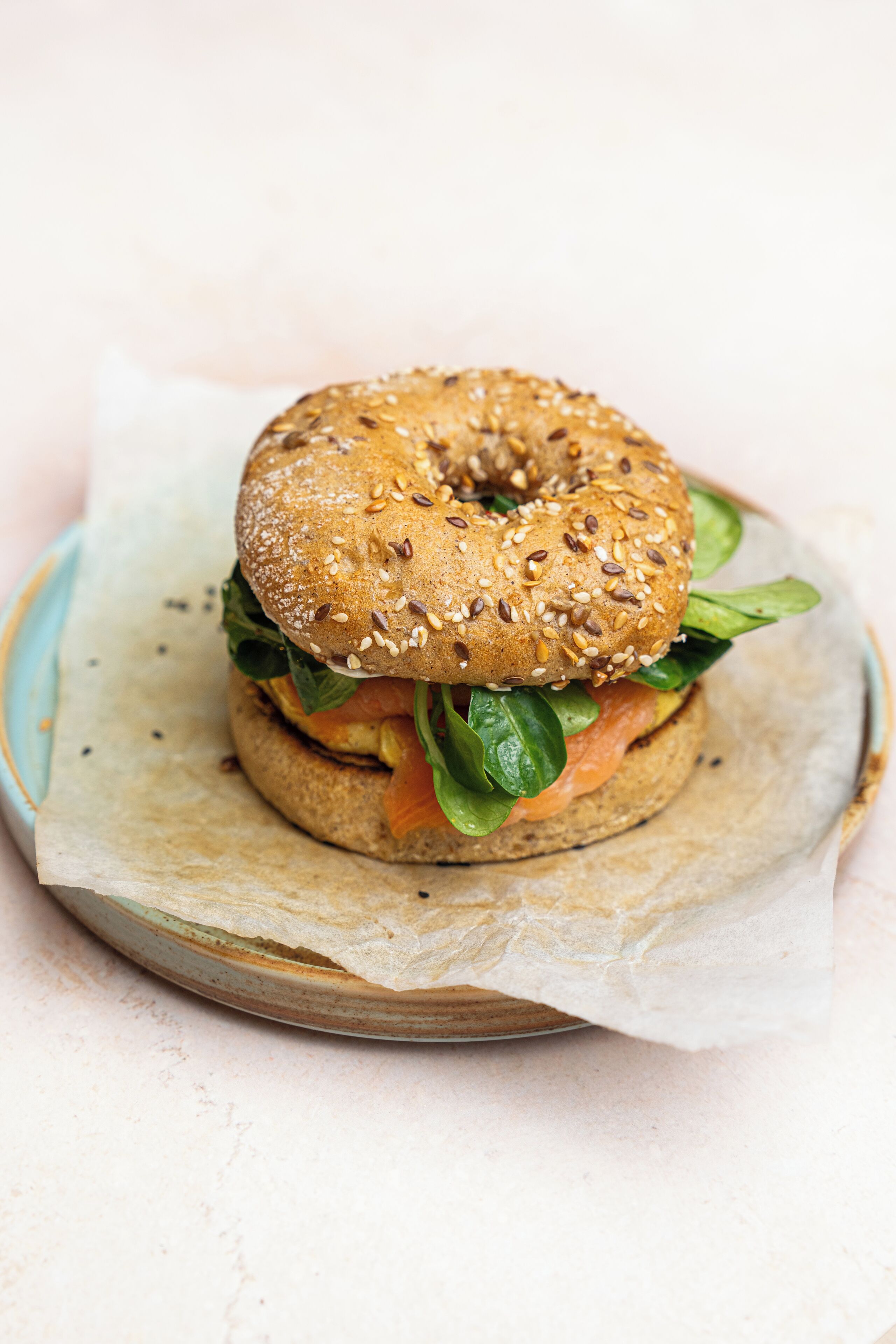 A bagel sandwich with sesame seeds and spinach on a plate.