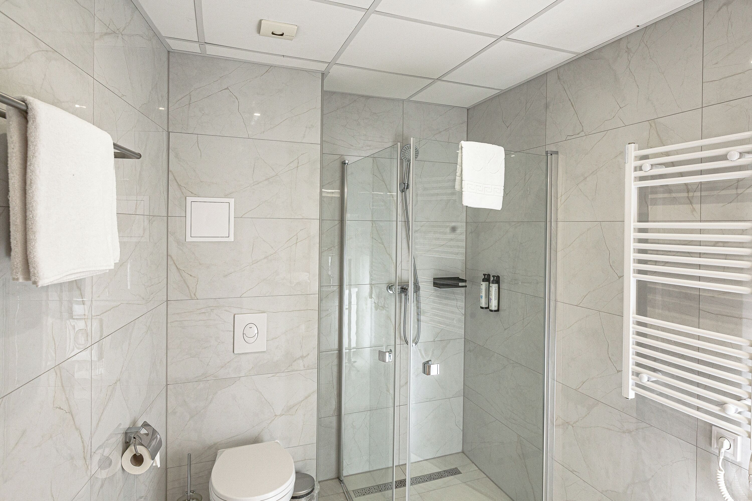 Un baño moderno con ducha acristalada, inodoro y barra para toallas.