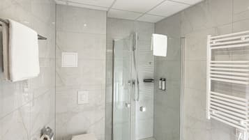Un baño moderno con ducha acristalada, inodoro y barra para toallas.