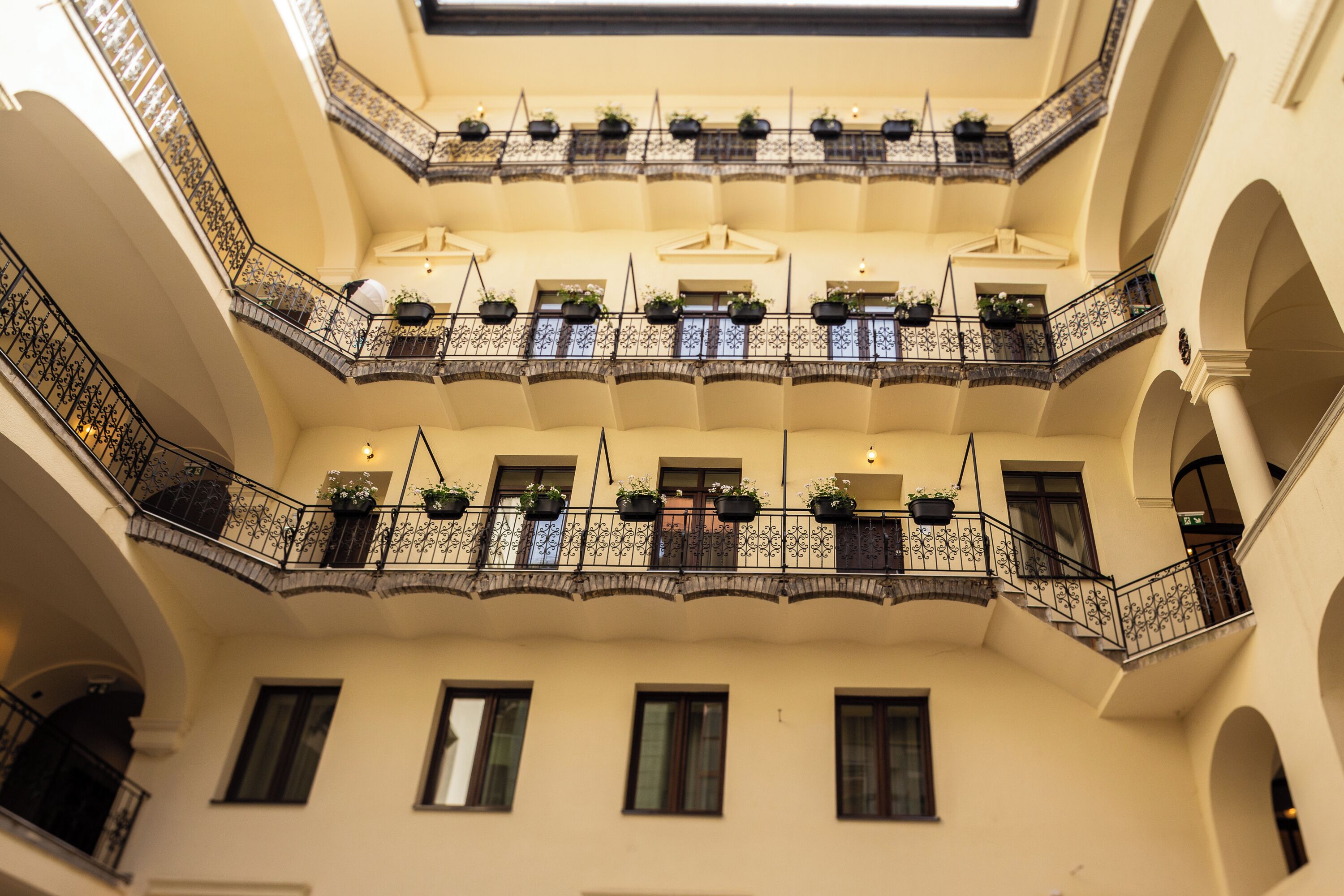 Un atrium à plusieurs niveaux, doté de balcons, chacun orné de rampes en fer forgé et de plantes en pot.