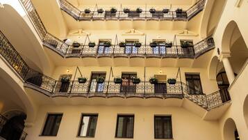 Un atrium à plusieurs niveaux, doté de balcons, chacun orné de rampes en fer forgé et de plantes en pot.