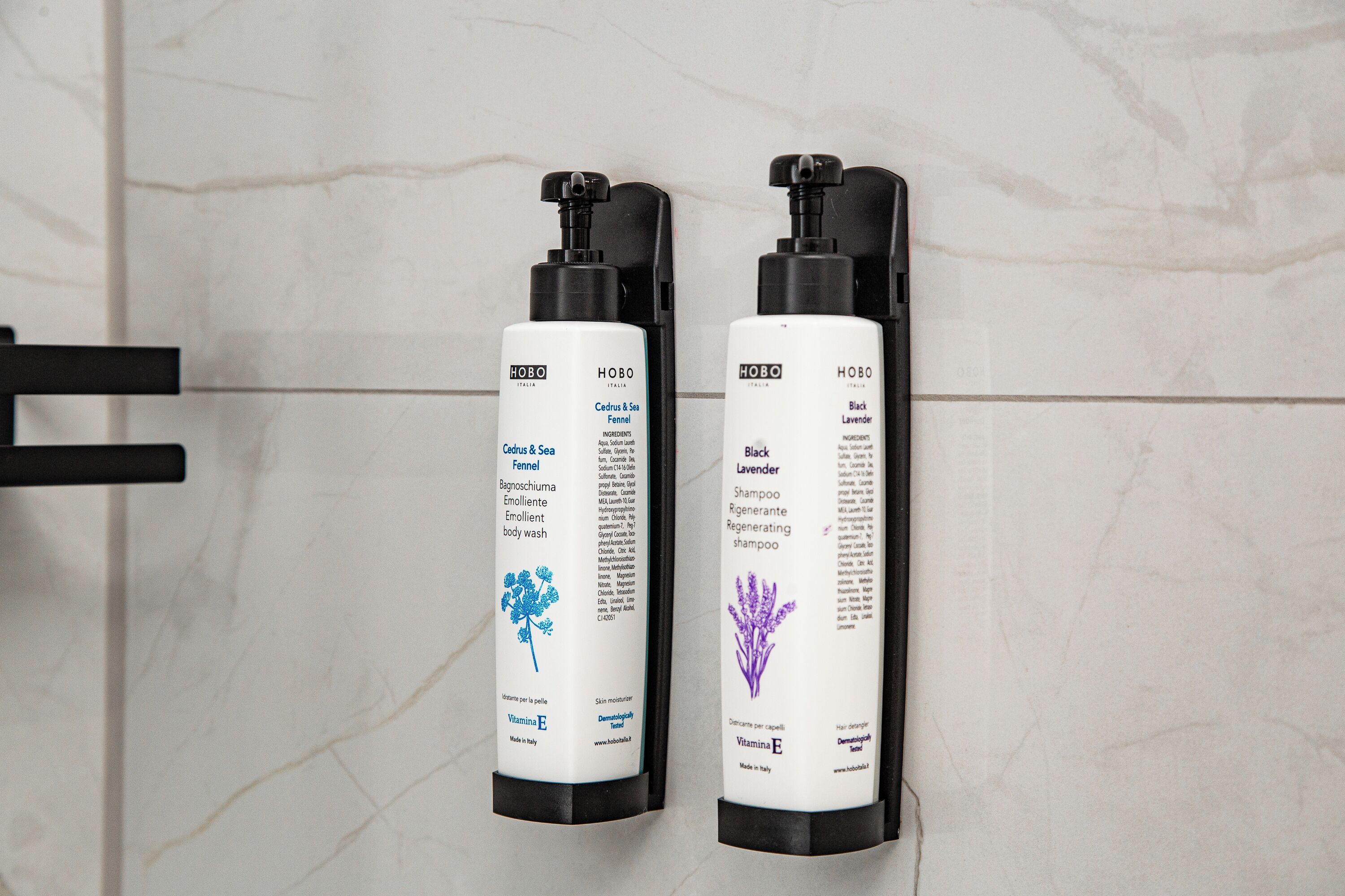 Two bottles of HOBO body wash on a tiled wall.