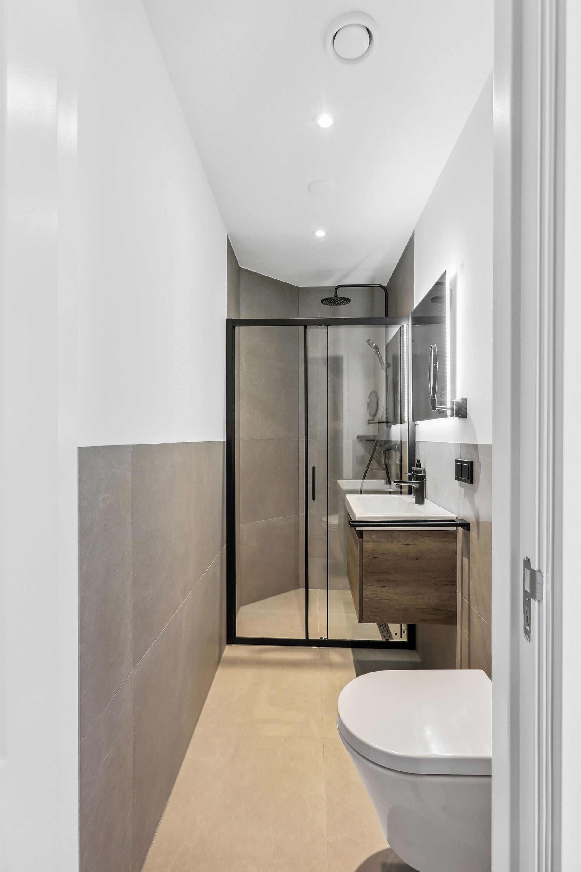 A modern bathroom with a glass shower enclosure, a white sink, and a toilet.