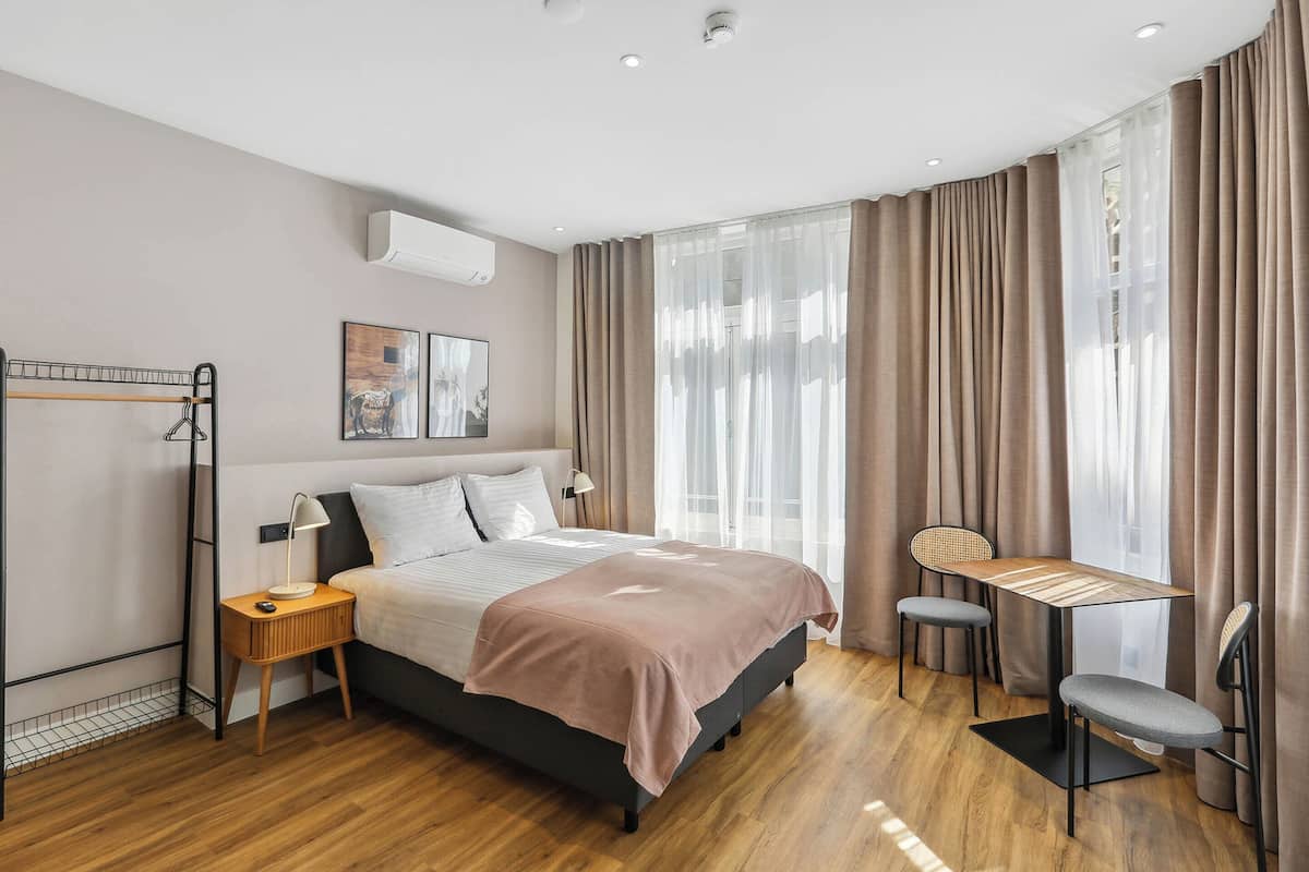 A modern bedroom with a bed, bedside table, lamp, and a small desk with chairs.