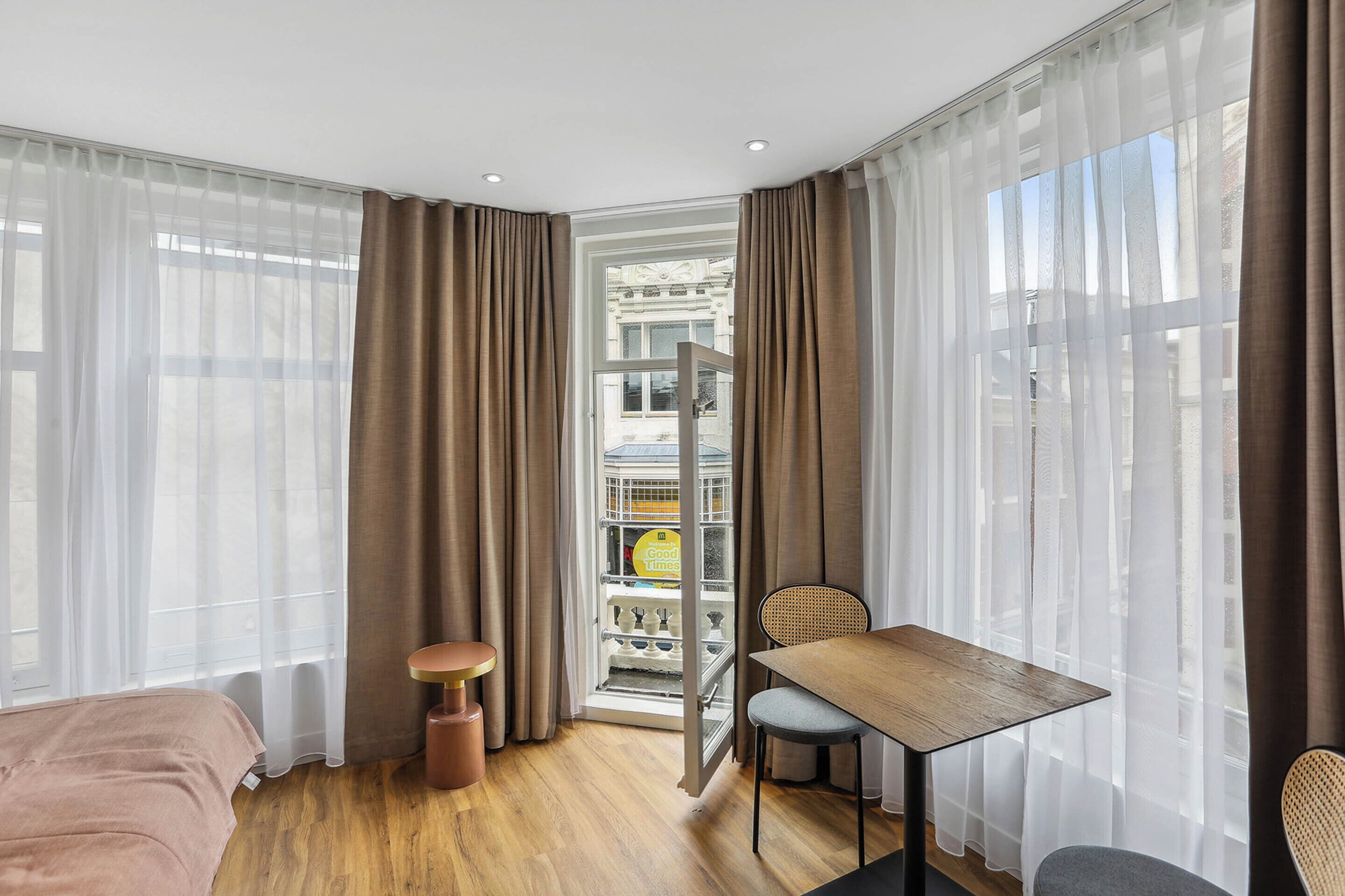 Ein Hotelzimmer mit Bett, Esstisch, Stuhl und einer Minibar.